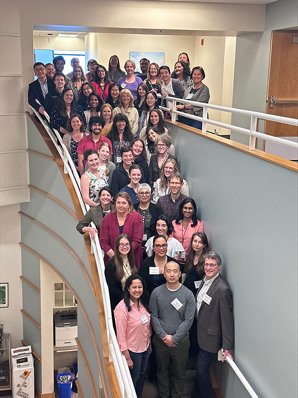 A group of about 60 people pose on the stairs for a group shot.