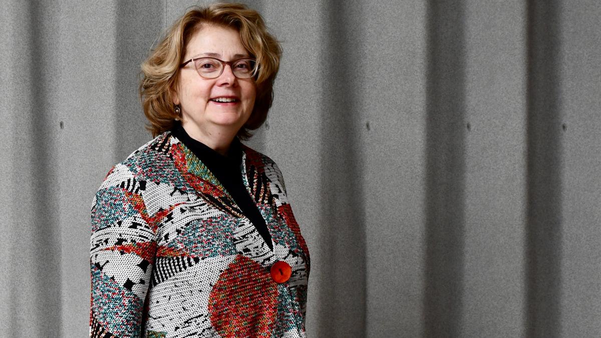 Dr. Faustman stands in front of a grey background.