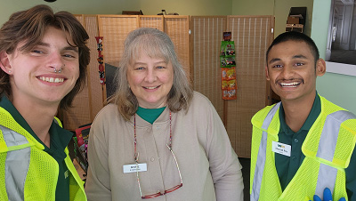 St. Louis stands smiling with two other people in an office.