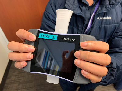 A person holds a spirometer, an instrument to measure lung function.