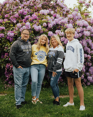 Hannah McKinley stands with three members of her and family in front of a rhododendron bush.