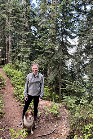 Claire Schollaert in a forest with her dog.