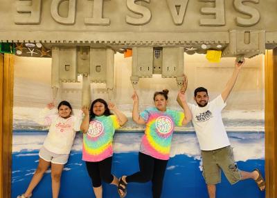 A family poses in front of a sandcastle background. 