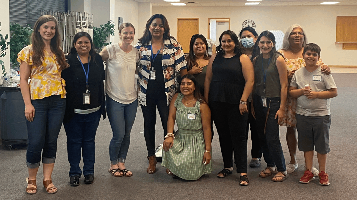 Ten women and a child stand together smiling in a group photo.