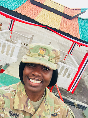 Photo of Medina smiling in front of a pavilion in Malaysia.