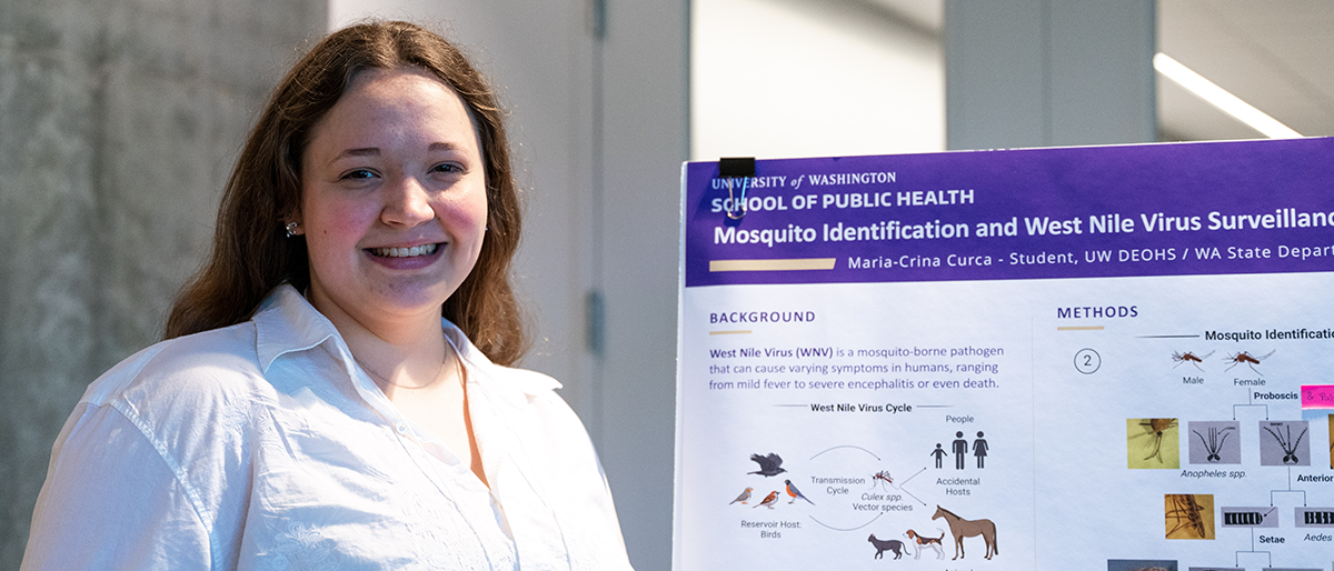 Maria-Crina Curca stands in front of her poster at the symposium.