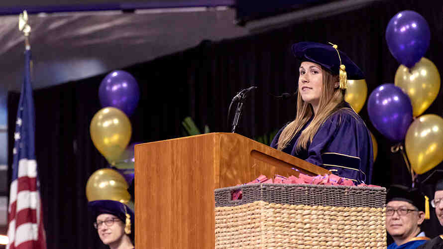 Miriam Caulkins speaking at a podium during the SPH graduation ceremony.