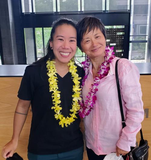 Two women smile with their arms around each other.