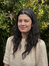 Headshot of Rachel Sklar standing in front of a green bush.