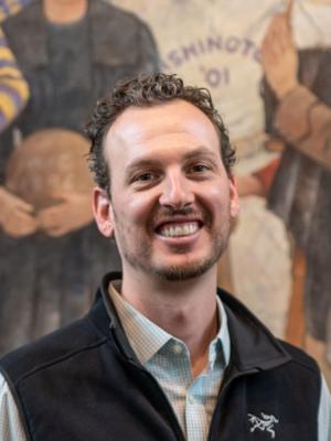 Dr Peckham, a young white man with curly brown hair and a beard