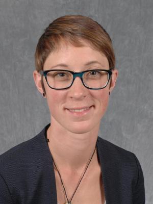 Headshot of Kathryn Kuehl, a young white woman with short red hair and blue glasses