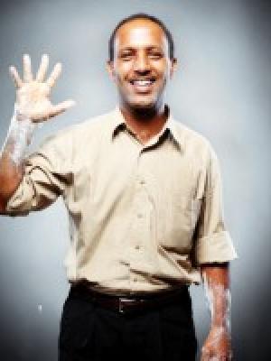 Dr Mazengia, a young black man waving with chalky hands