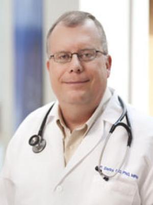 Headshot of Dr Darby, an older balding white man with gray hair and glasses in a lab coat