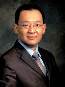 Jia-Hua Lin, a middle-aged Asian man with small glasses wearing a suit