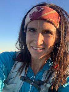 Headshot of Liz Walker, a. young white woman in hiking garb with long brown hair