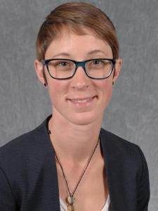 Headshot of Kathryn Kuehl, a young white woman with short red hair and blue glasses