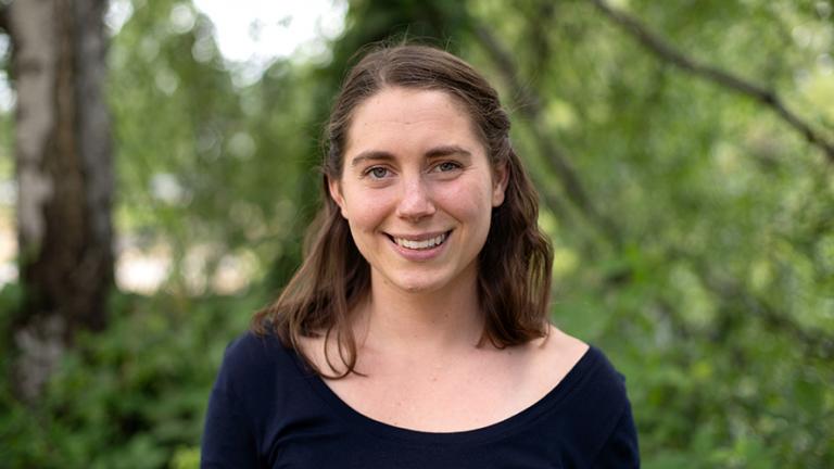 Headshot of Claire Pendergrast standing in front of a blurry leafy background.  Photo: Elizar Mercado