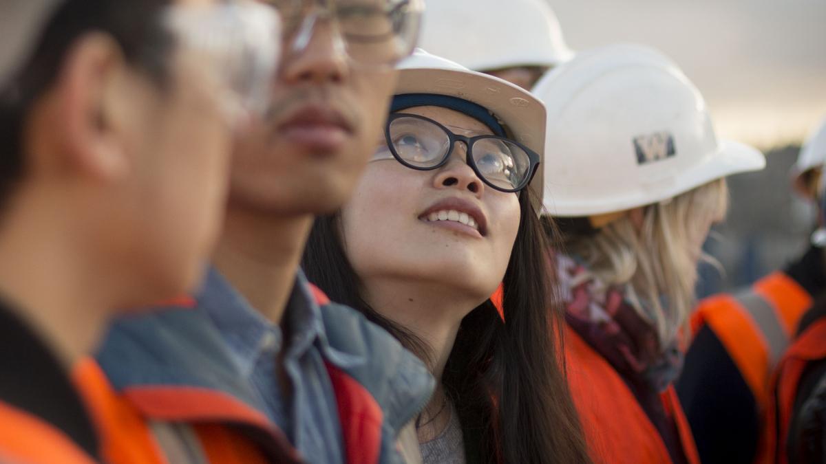 Young woman in hardhat looking up