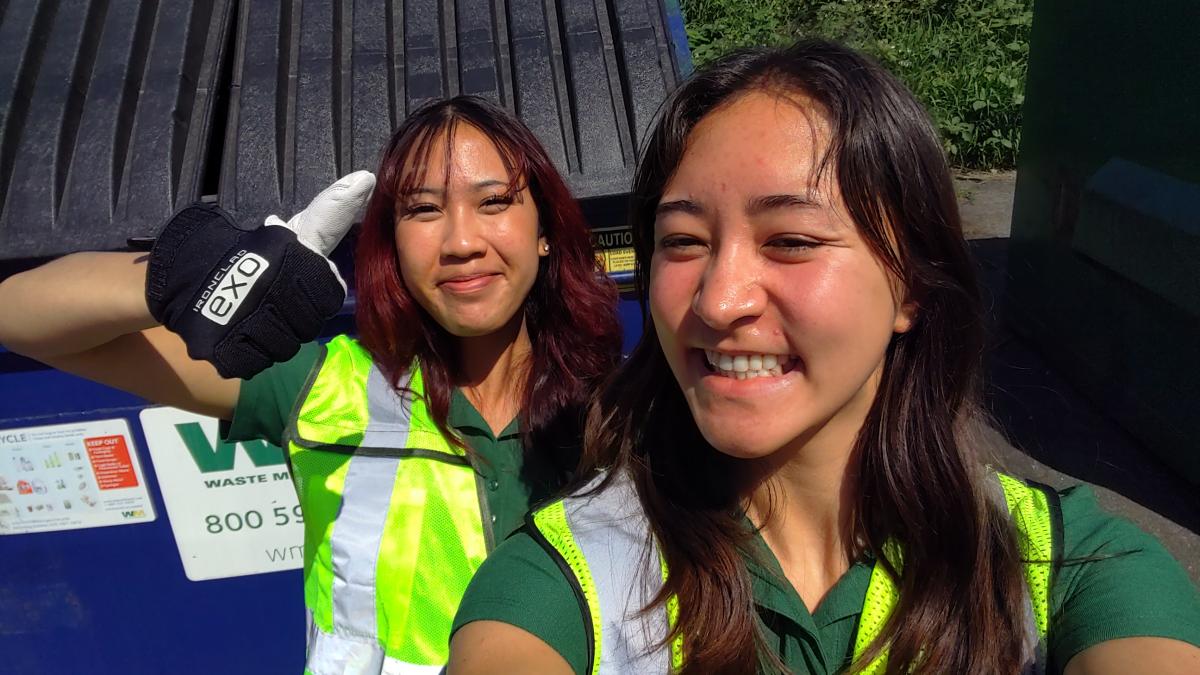 Kai and Allison two undergraduate students smiling at the camera in high vis vests