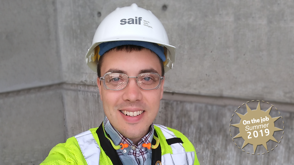 A young man with a hardhat looks into the camera.