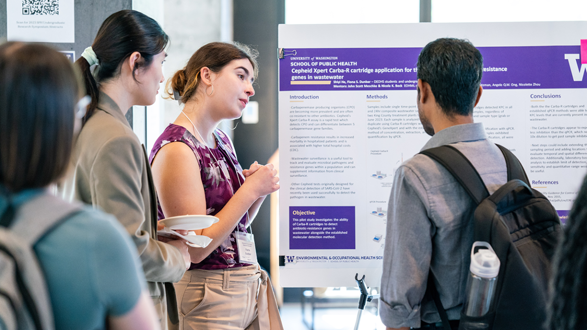 Several students stand around a poster during the School of Public Health Undergraduate Symposium.