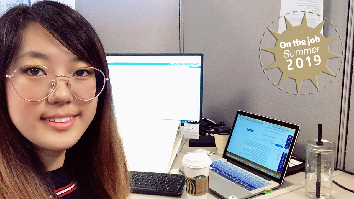 A young woman sits at a computer work station.