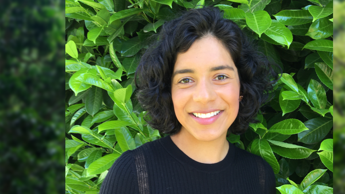 Portrait of Magali Blanco in front of greenery.