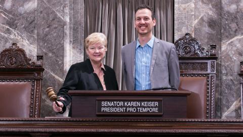 Two people standing at a podium, one holding a gavel.