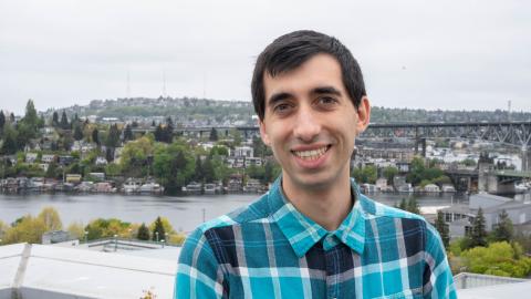 Joey Teresi smiles with a waterway, trees and a bridge behind him.