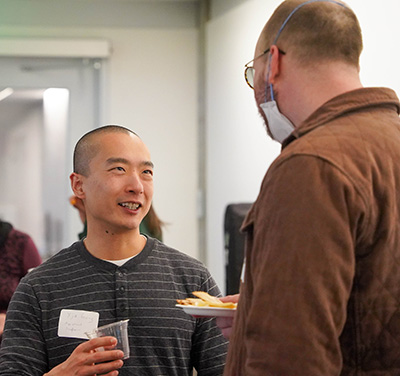 Geng talking to another faculty member at an event. 