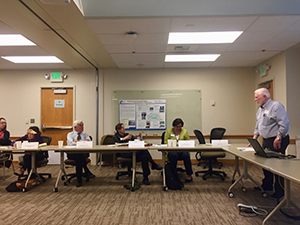 Tom Fox stands at the front of the room while presenting about wastewater.